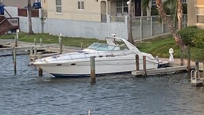 Un barco amarrado en un puerto deportivo con una casa al fondo.