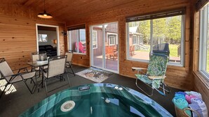A wooden cabin interior with a hot tub, dining area, and large windows. - Lakeside Lodge on Lake Huron (Saint Ignace)