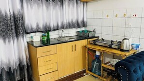 A compact kitchen with wooden cabinets, a sink, a stove, and a small countertop. - Beautiful & cosy studio, 5 mins from two rivers (Ruaka)