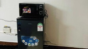 A compact, black refrigerator with a digital display and a small freezer compartment on top. It has several stickers, including one for a health-related certification. - Beautiful & cosy studio, 5 mins from two rivers (Ruaka)