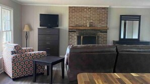 A living room with a fireplace, a sofa, a coffee table, and a TV. - Camden Cottage (Camden)