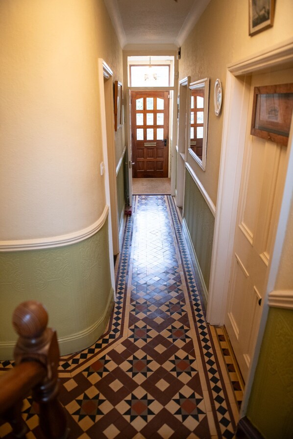 A hallway with patterned flooring, doors, and a wooden handrail.