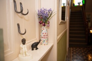A hallway with a decorative vase on a shelf, a coat hook, and a small figurine. - Milton House-  Studio Apartment .Whitfield Suite (Leyburn)