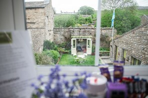 Uitzicht op een stenen gebouw met een kleine tuin en een deur naar een kamer.