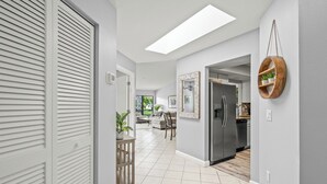 Een moderne keuken met een roestvrijstalen koelkast, een houten eettafel en een hangende plantenplank.