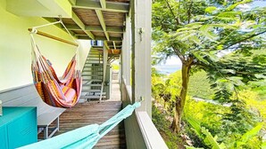 Un balcón con hamaca, terraza de madera y vistas a exuberante follaje.