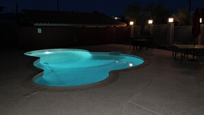 Ein Pool mit wellenförmigem Design, umgeben von einer eingezäunten Terrasse mit Sitzgelegenheiten im Freien.