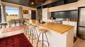 A modern kitchen with a central island, bar stools, and a dining area with a view.