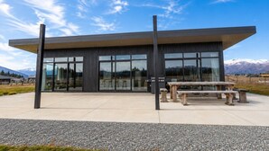 A modern building with large windows, a flat roof, and a gravel patio with benches. - Black Box, Twizel, FREE WIFI (Twizel)