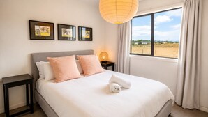 A bedroom with a bed, two nightstands, a lamp, and a window with a view.