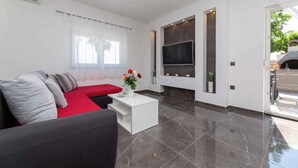 A modern living room with a red sofa, a white coffee table, and a flat-screen TV mounted on the wall. - Villa Mia with pool in Garica (Garica)