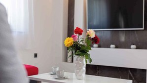 A modern room with a white table, a vase of flowers, and a flat-screen TV mounted on the wall. - Villa Mia with pool in Garica (Garica)