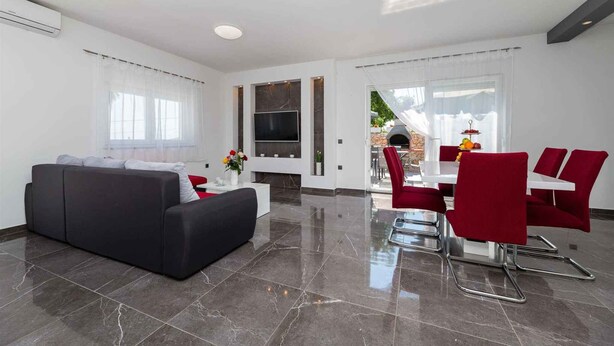 A modern living room with a black sofa, a dining area with red chairs, a flat-screen TV, and a fireplace. - Villa Mia with pool in Garica (Garica)