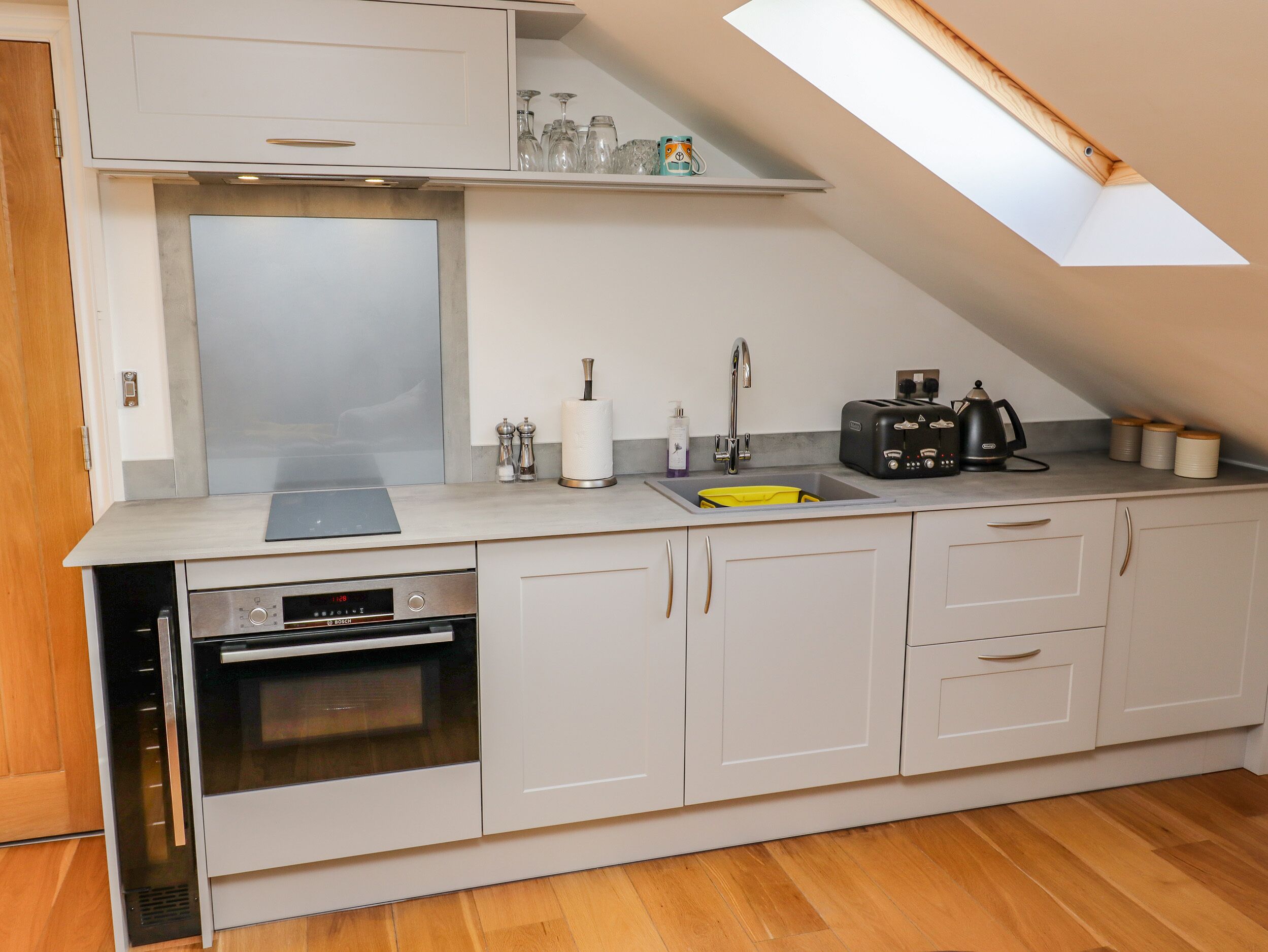A modern kitchen with white cabinets, a built-in oven, a sink, and a toaster.