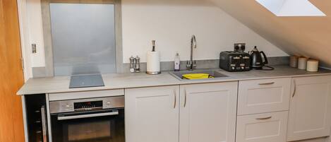 A modern kitchen with white cabinets, a built-in oven, a sink, and a toaster.