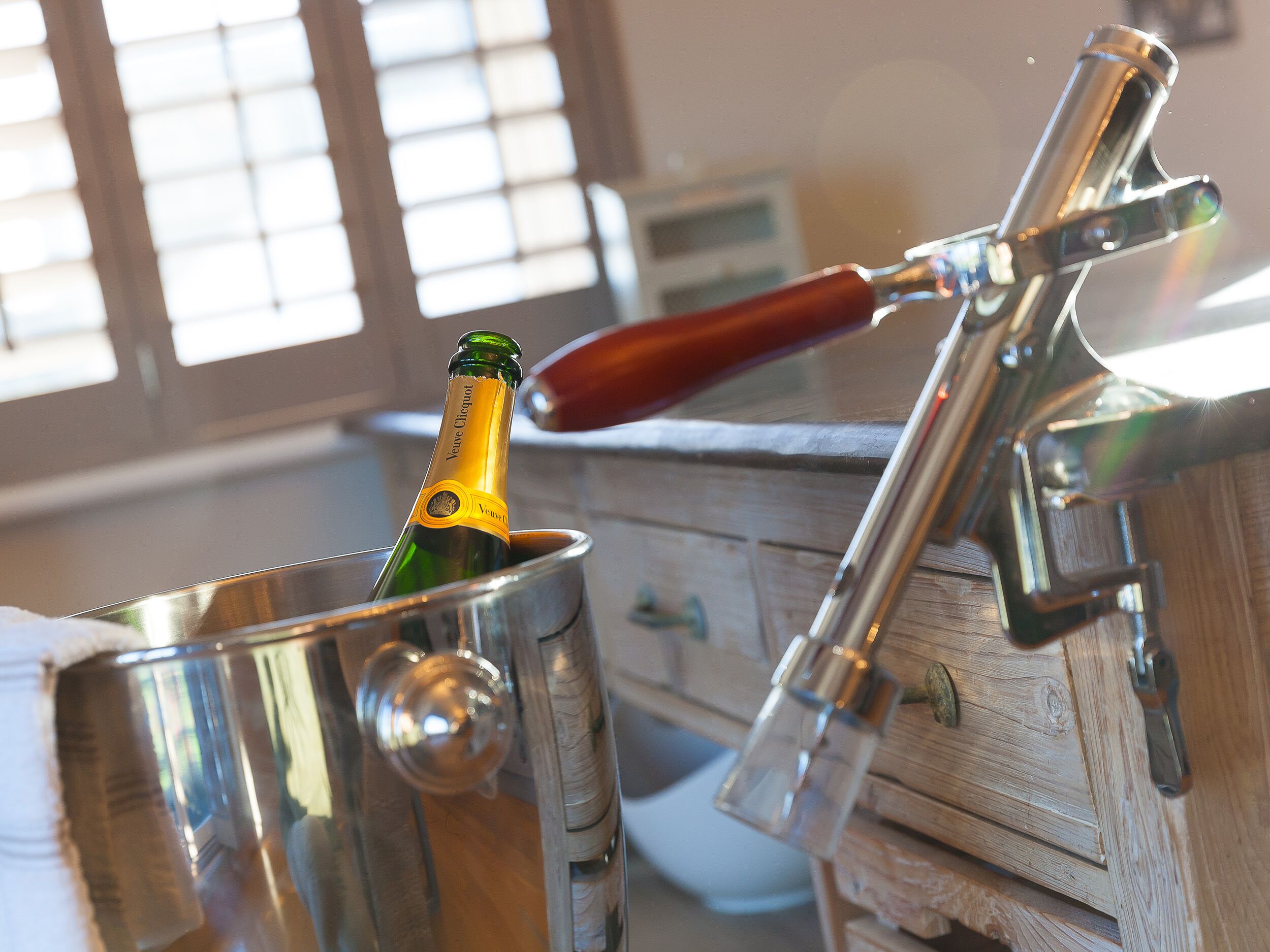 Une bouteille de champagne dans un seau en métal, posée sur un meuble en bois.