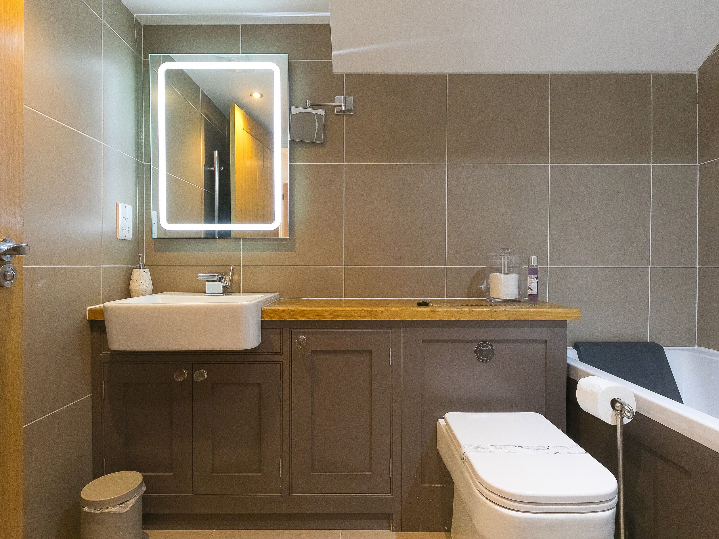 Une salle de bain moderne avec un grand miroir, un lavabo, des toilettes et une baignoire.