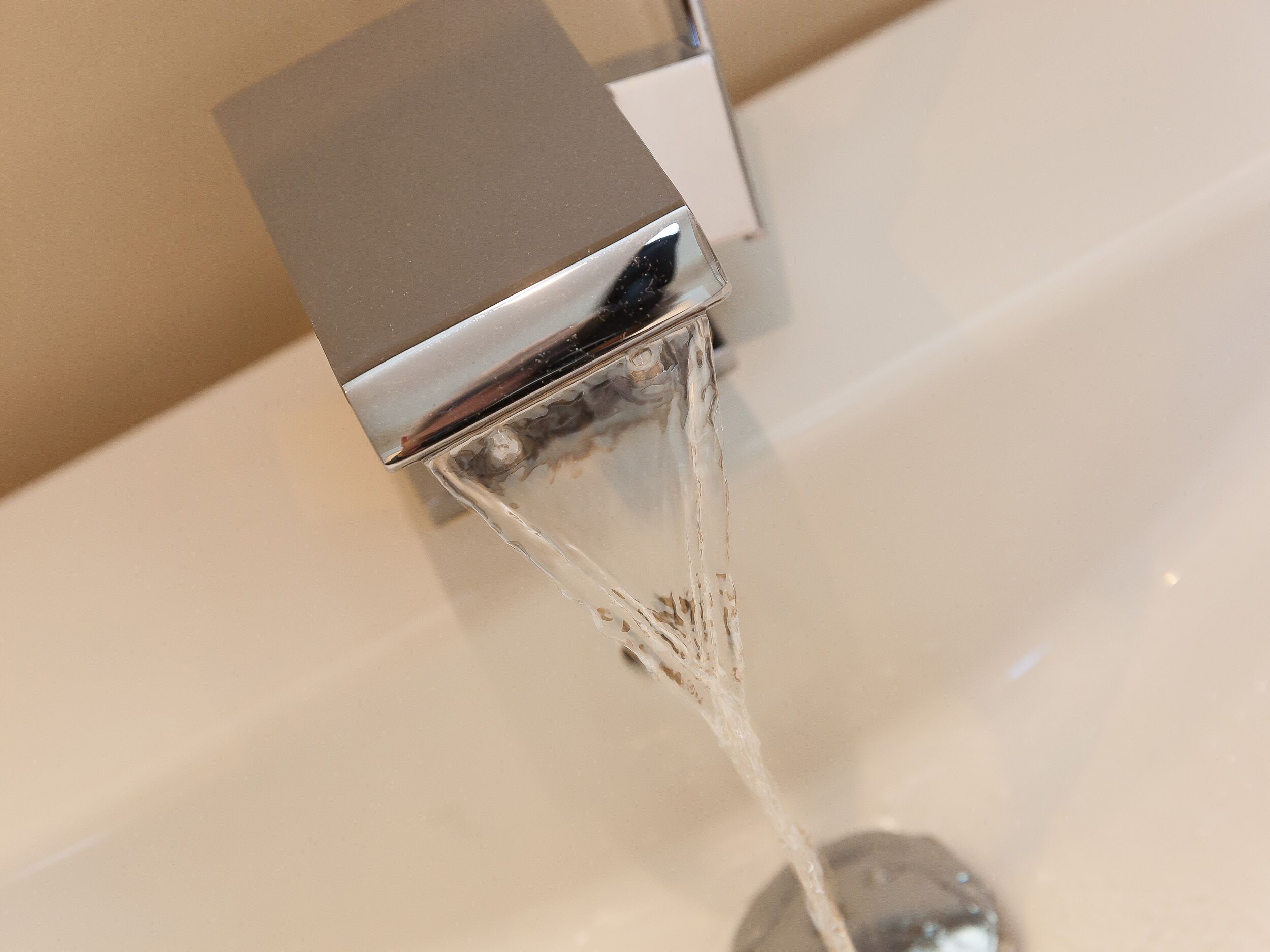 A modern bathroom with a chrome faucet and clear water running into a sink.