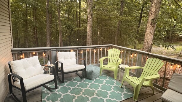 A wooden deck with outdoor furniture, string lights, and a patterned rug. - The Hangout- Comfy Getaway in the Woods (Hot Springs)