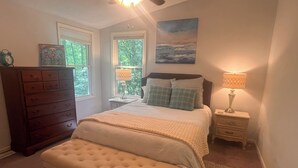 A bedroom with a bed, a bench, a dresser, two bedside tables, and a painting on the wall. - The Hangout- Comfy Getaway in the Woods (Hot Springs)