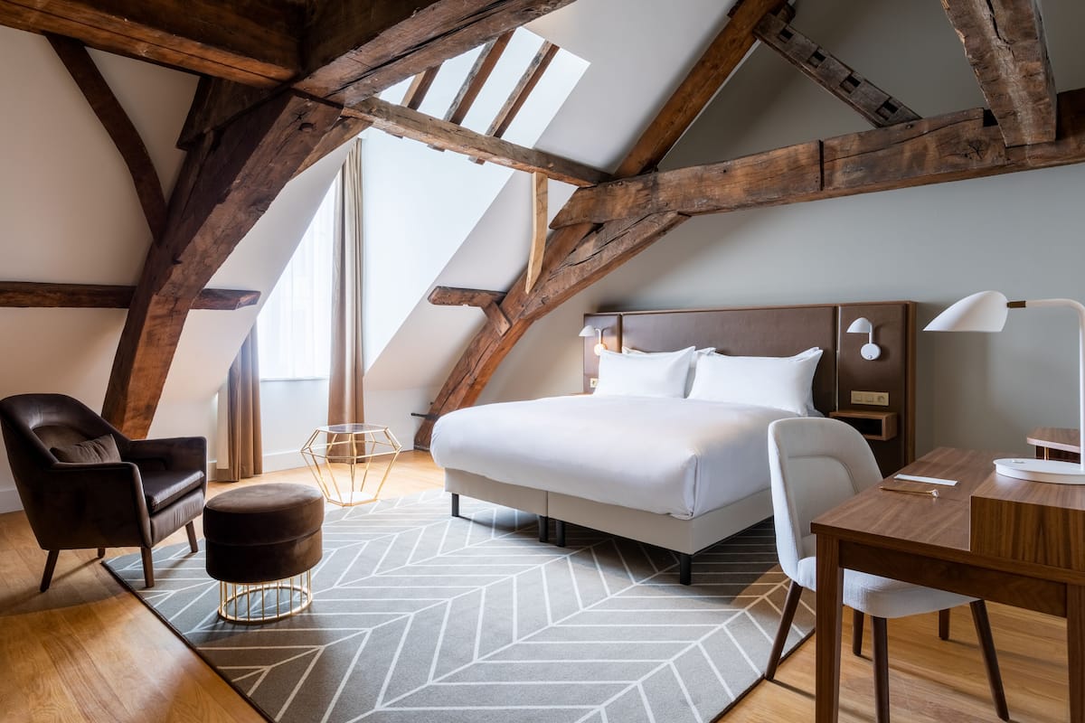 A modern bedroom with a large bed, a desk, a chair, and a sofa.