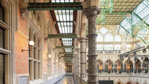 An indoor corridor with checkered flooring, ornate columns, and a high ceiling with green metalwork. - Sapphire House Antwerp, Autograph Collection (Antwerp)