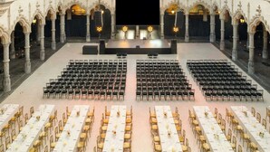 A large hall with rows of tables and chairs, a stage, and ornate architecture. - Sapphire House Antwerp, Autograph Collection (Antwerp)