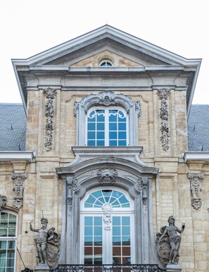 A classical building with a symmetrical facade, featuring a central arched window with a decorative crest, flanked by statues and ornate stonework. - Sapphire House Antwerp, Autograph Collection (Antwerp)