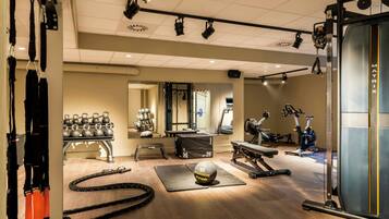 Une salle de sport équipée de matériel d’exercice, d’un rameur et d’un tapis de course.