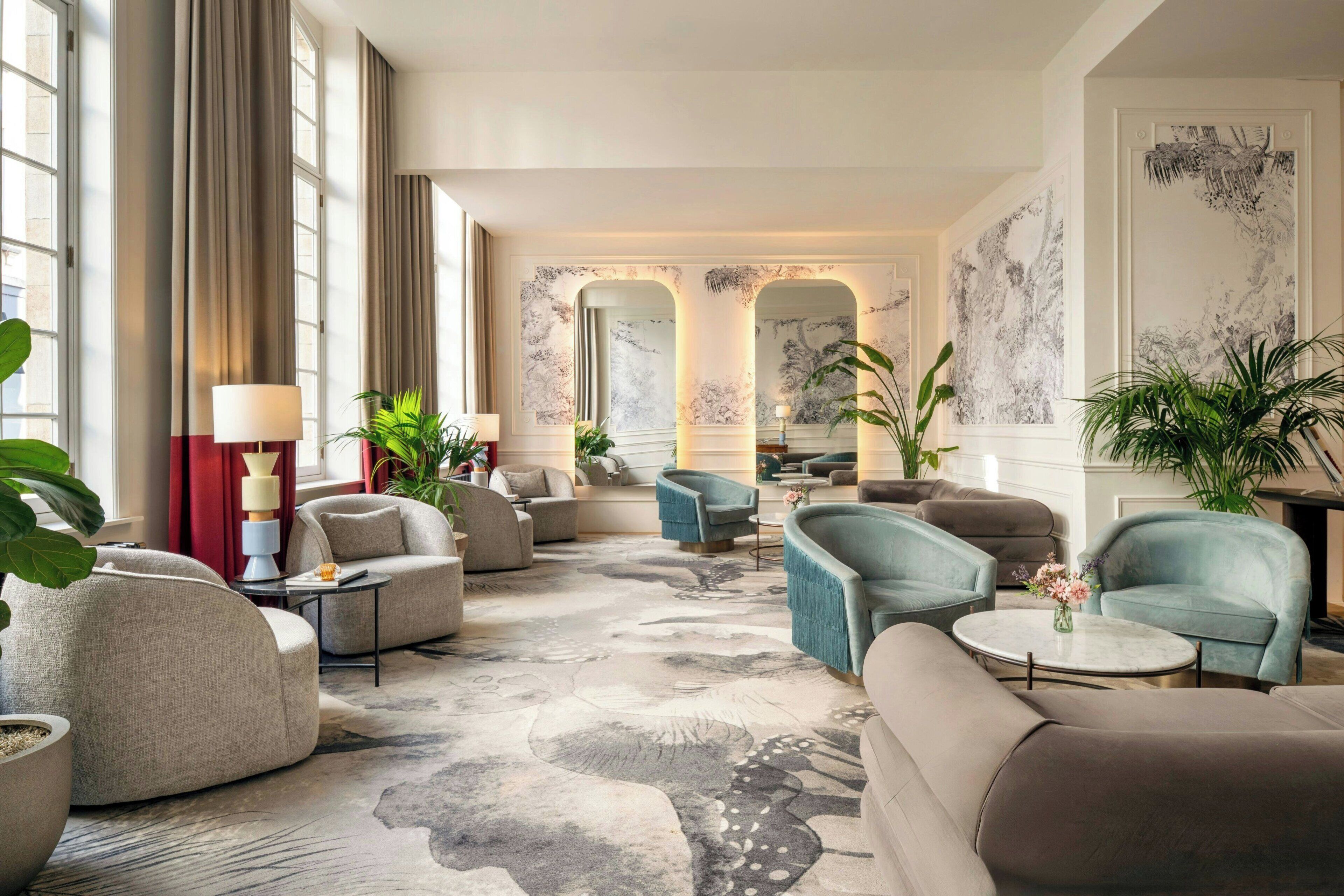 Eine großzügige Lobby mit mehreren Sitzbereichen, großen Fenstern und dekorativer Wandkunst.