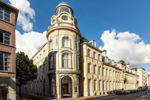 Un edificio histórico con una cúpula destacada y ventanas arqueadas, situado en una calle de la ciudad.