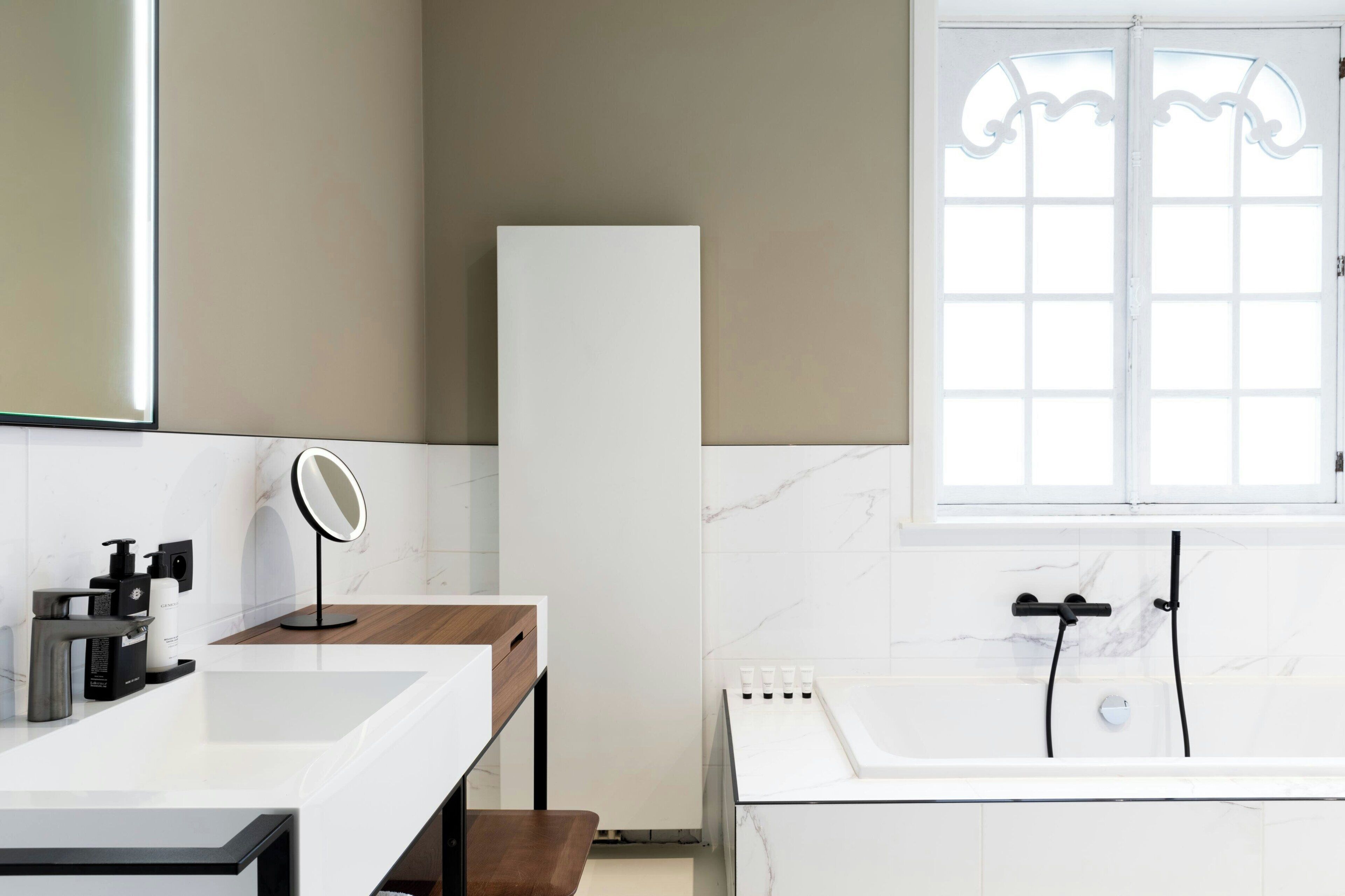 Ein modernes Badezimmer mit Waschbecken, Spiegel und Badewanne in Weiß.