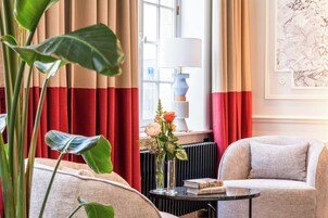 Una habitación con un sofá, una mesita con un libro, una lámpara y una ventana con cortinas.