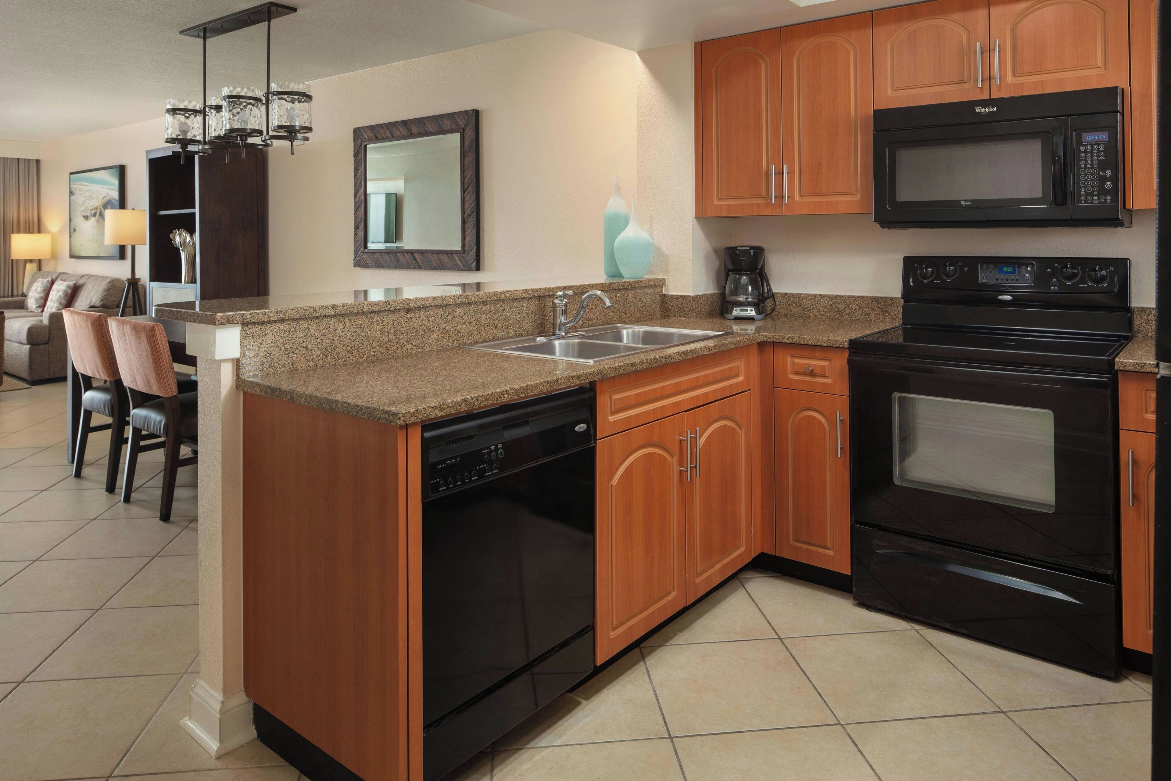 A modern kitchen with granite countertops, wooden cabinets, a dishwasher, a stove, and a microwave.