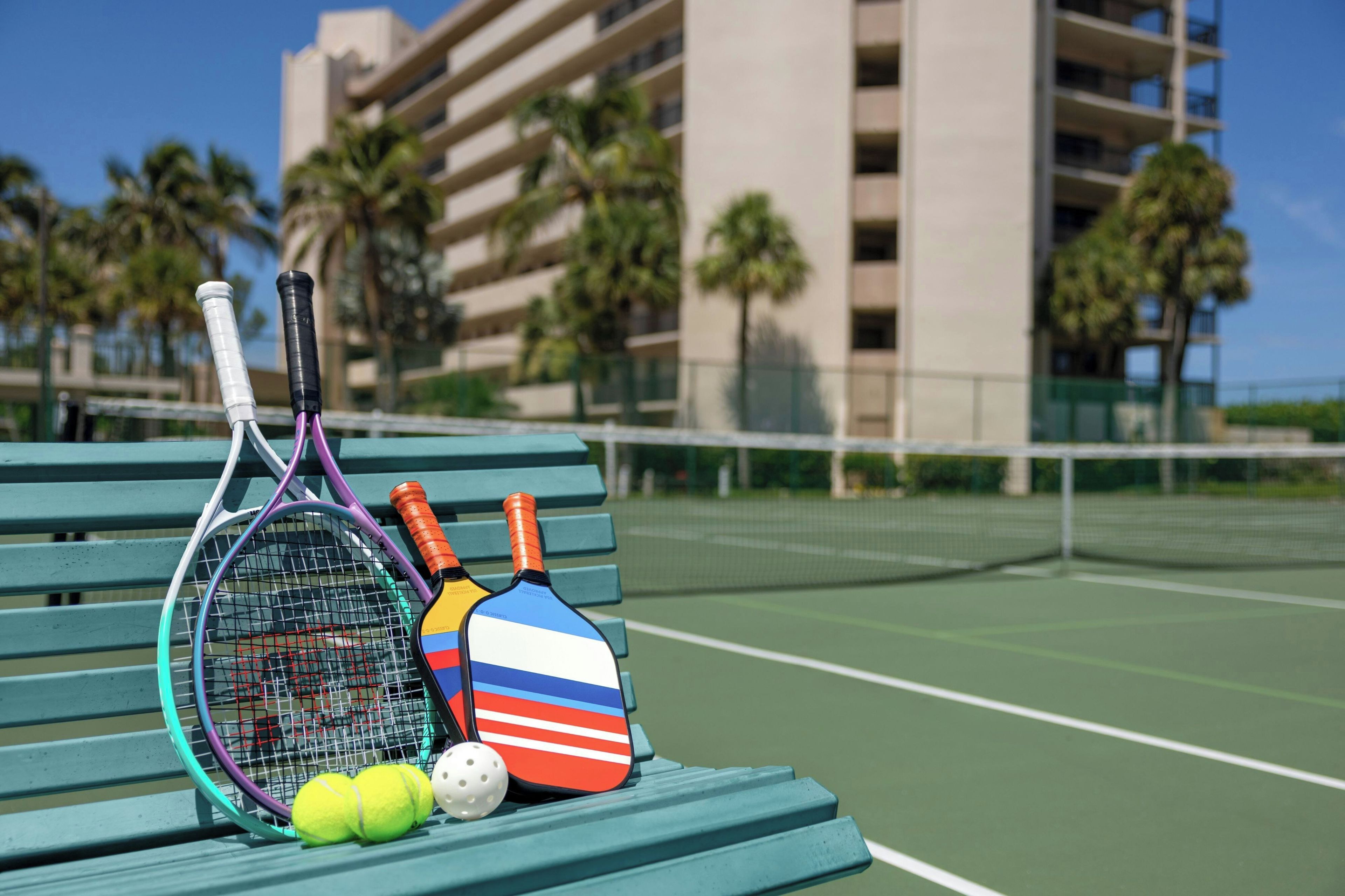 Un court de tennis avec un banc, des raquettes de tennis et des balles.