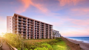 A multi-story hotel with balconies, located near a beach with a wooden walkway leading to the building. - Vistana Beach Club (Jensen Beach)