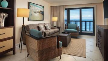 Habitación de hotel con sofá, sillón y vistas al mar.