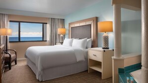 A hotel room with a large bed, two bedside tables, a desk, and a view of the ocean. - Vistana Beach Club (Jensen Beach)