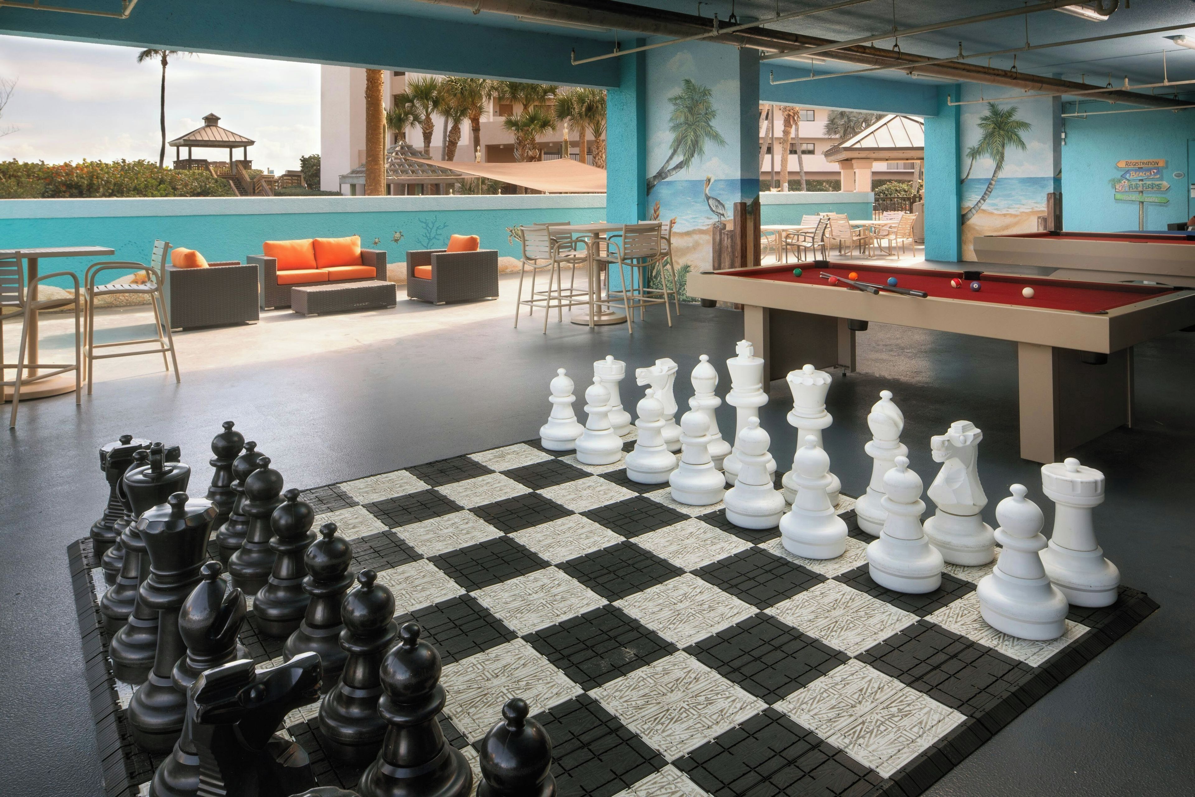 A pool area with a checkered floor, a pool table, and a chess set.