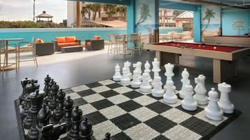 A pool area with a checkered floor, a pool table, and a chess set.