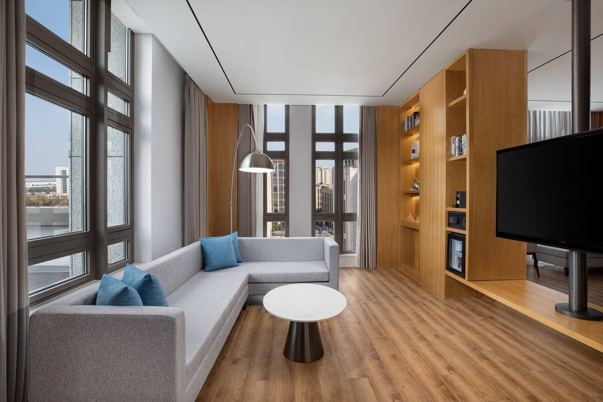 A modern living room with a grey sofa, a round coffee table, and a flat-screen TV.