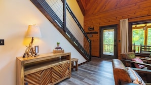 Een houten interieur met een trap, een bank en een console tafel met decoratieve objecten.