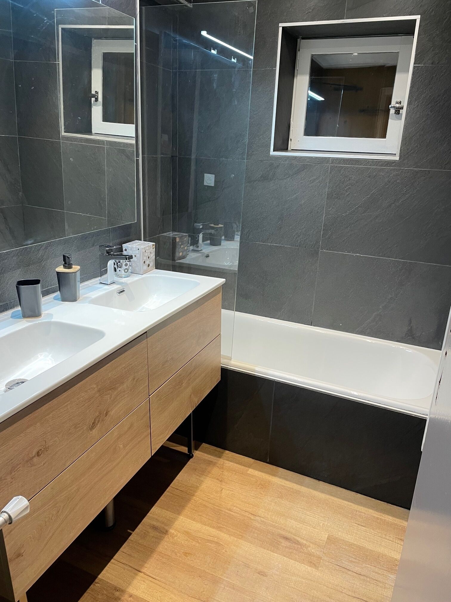 Ein modernes Badezimmer mit zwei Waschbecken, einem Spiegel und einer Badewanne.