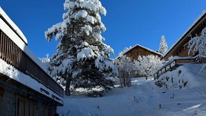 Schneebedeckte Landschaft mit einem Holzhaus und einem großen Baum.