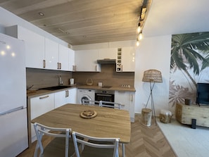 Una cucina moderna con mobili bianchi, un tavolo da pranzo in legno e un'ampia finestra.