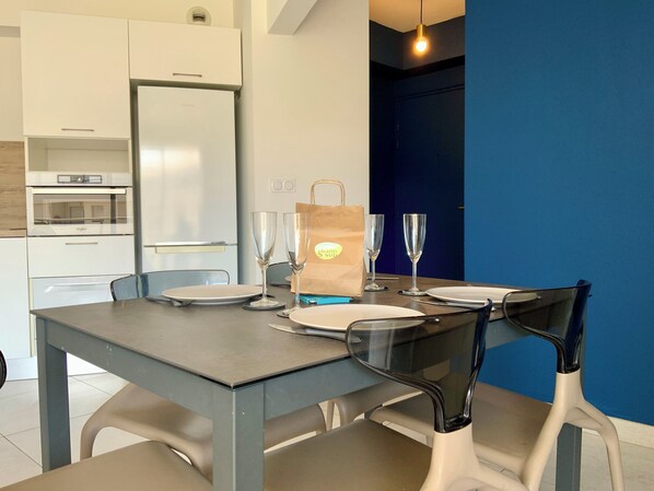 A dining area with a table set for four, a bag, and a whiteboard in the background.