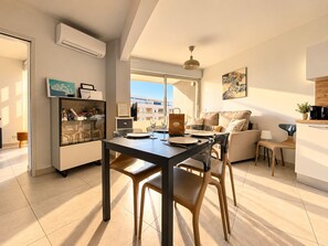 A modern apartment with a dining area, a sofa, and a kitchen.