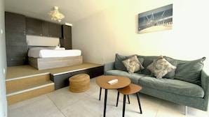 A modern room with a bed, a sofa, a coffee table, and a painting on the wall.