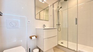 Une salle de bain moderne équipée de toilettes, d’un lavabo et d’une douche.