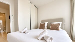 Une chambre d’hôtel avec un grand lit, deux oreillers et deux serviettes enroulées.